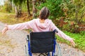 Young happy handicap woman in wheelchair on road in hospital park enjoying freedom. Paralyzed girl in invalid chair for disabled Royalty Free Stock Photo