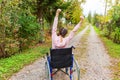 Young happy handicap woman in wheelchair on road in hospital park enjoying freedom. Paralyzed girl in invalid chair for disabled Royalty Free Stock Photo