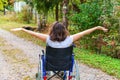 Young happy handicap woman in wheelchair on road in hospital park enjoying freedom. Paralyzed girl in invalid chair for disabled Royalty Free Stock Photo