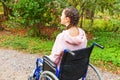 Young happy handicap woman in wheelchair on road in hospital park waiting for patient services. Paralyzed girl in invalid chair Royalty Free Stock Photo