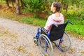 Young happy handicap woman in wheelchair on road in hospital park waiting for patient services. Paralyzed girl in invalid chair Royalty Free Stock Photo