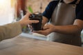 Young happy handsome man barista serving hot coffee cup to friendly female customer over counter in modern cafe coffee shop Royalty Free Stock Photo