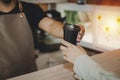 Young happy handsome man barista serving hot coffee cup to friendly female customer over counter in modern cafe coffee shop Royalty Free Stock Photo