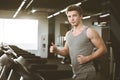 Young happy handsome man in grey sportswear in fitness club. Cardio workout, running on treadmill. Healthy lifestyle Royalty Free Stock Photo