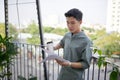 Young happy handsome man sitting and reading book, drinking beverage on outside balcony