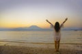 Young happy and healthy woman spreading arms free standing on sand beach looking at horizon sea water and volcano landscape on the Royalty Free Stock Photo