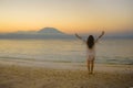 Young happy and healthy woman spreading arms free standing on sand beach looking at horizon sea water and volcano landscape on the Royalty Free Stock Photo