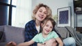 Young happy hipster mother and daughter waving hands, looking at webcam talking to camera. Video conference calling in