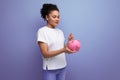 young happy hispanic brunette woman saving money for a dream in a pink piggy bank Royalty Free Stock Photo