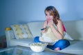 Young happy hispanic latin woman at home sofa couch watching television eating popcorn relaxed cheerful enjoying alone funny TV co Royalty Free Stock Photo