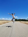 Young happy Hispanic teenage boy jumping on an asphalt road in the countryside on a sunny day Royalty Free Stock Photo