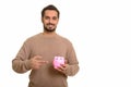Young happy Indian man holding piggy bank and pointing finger Royalty Free Stock Photo