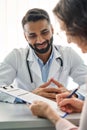 Smiling Indian doctor consulting female patient in clinic hospital. Vertical. Royalty Free Stock Photo