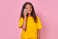 Young happy Indian woman teen making call on mobile phone stands in studio Royalty Free Stock Photo