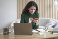 Young happy italian woman freelancer sitting at workplace with laptop at home and using mobile phone Royalty Free Stock Photo