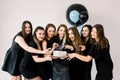 Young happy ladies in black dresses celebrating birthday at studio. Girl best friends having fun holding birthday cake