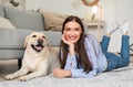 Young happy lady with her dog lying on floor