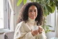 Young happy latin woman drinking tea or coffee relaxing at home. Royalty Free Stock Photo