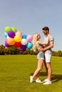 Young happy lovers having date in the park and holding balloons Royalty Free Stock Photo