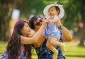 Young happy and loving Asian Chinese parents couple enjoying together with sweet daughter baby girl sitting on grass at green city Royalty Free Stock Photo