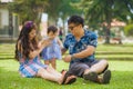 Young happy and loving Asian Japanese parents couple enjoying together with sweet daughter baby girl sitting on grass at green cit Royalty Free Stock Photo