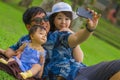 Young happy loving Asian Japanese family with parents and sweet baby daughter at city park together with father taking selfie pic Royalty Free Stock Photo