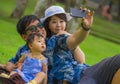 Young happy loving Asian Korean family with parents and sweet baby daughter at city park together with father taking selfie pic Royalty Free Stock Photo