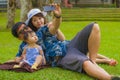 Young happy loving Asian Korean family with parents and sweet baby daughter at city park together with father taking selfie pic Royalty Free Stock Photo