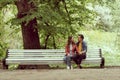 Young, happy, loving couple having date on the bench in the park. Relations, friendship and love. Royalty Free Stock Photo