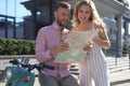 Young happy loving couple looking at map and sitting on scooter Royalty Free Stock Photo