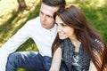 Young, happy, loving couple, sitting together on the grass in the Park, and enjoying each other, advertising, and inserting text Royalty Free Stock Photo