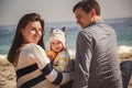 Young happy loving family with small child, enjoying time at beach sitting and hugging near ocean Royalty Free Stock Photo