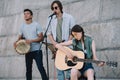 Young and happy male and female street musicians playing guitars and djembe Royalty Free Stock Photo