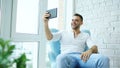 Young happy man have online video chat using digital tablet computer sitting on balcony in modern loft apartment Royalty Free Stock Photo