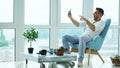 Young happy man have online video chat using digital tablet computer sitting on balcony in modern loft apartment Royalty Free Stock Photo