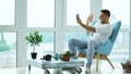 Young happy man have online video chat using digital tablet computer sitting on balcony in modern loft apartment Royalty Free Stock Photo