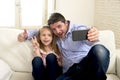 Young happy man having fun with his little cute blond daughter taking selfie photo with mobile phone