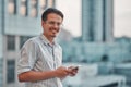 Man on the street. Young happy man holding a phone in his hand and smilling Royalty Free Stock Photo