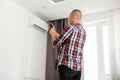 Young Happy man Holding Remote Control Air Conditioner In House Royalty Free Stock Photo