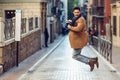 Young happy man jumping wearing winter clothes in urban background Royalty Free Stock Photo