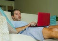 Young happy man lying at home sofa couch relaxed using internet on laptop computer watching online movie or working as independent Royalty Free Stock Photo