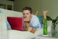 Young happy man lying at home sofa couch relaxed using internet on laptop computer watching online movie or working as independent