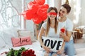 Young happy man makes an offer of hands and hearts to his beloved girl. Closing her eyes with hand, he holds in front of her a red Royalty Free Stock Photo