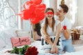 Young happy man makes an offer of hands and hearts to his beloved girl. Closing her eyes with hand, he holds in front of her a red Royalty Free Stock Photo