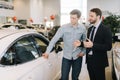 Young happy man preparing to buy new car in auto dealership. Royalty Free Stock Photo