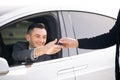 Young Happy Man Receiving Car Keys to Her New Automobile. Dealer giving key to new owner in auto show or salon. Car Royalty Free Stock Photo