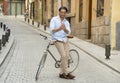 Young happy man smiling using mobile the phone on vintage cool retro bike Royalty Free Stock Photo