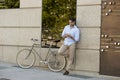 Young happy man smiling using mobile phone on vintage cool retro bike Royalty Free Stock Photo