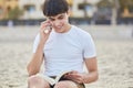 Young happy man talking on mobile and reading book outside Royalty Free Stock Photo