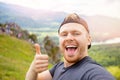 Young happy man traveler make selfie on background of mountains in summer sunset. Concept adventure trip vacation Royalty Free Stock Photo